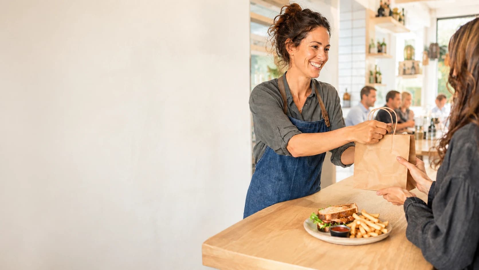A restaurant team member handing a takeaway order to a guest